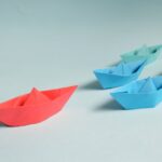 Colorful origami paper boats arranged to depict leadership and teamwork concepts.